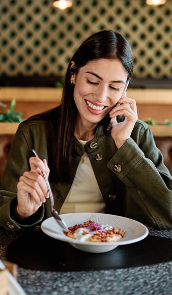 Clienta sonriente disfrutando de un plato en la mesa de un restaurante