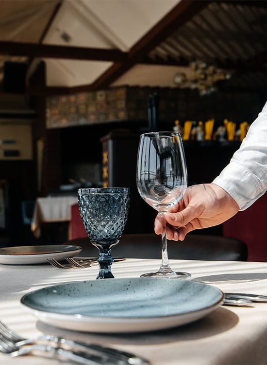 Camarero colocando una copa de vino en una mesa montada de un restaurante en Barcelona