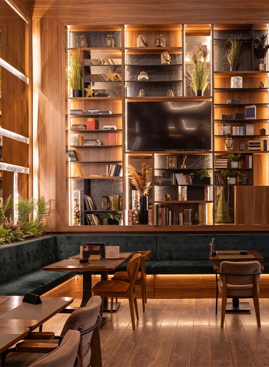 Rincón acogedor de un restaurante en Madrid con una gran estantería de madera y banco tapizado