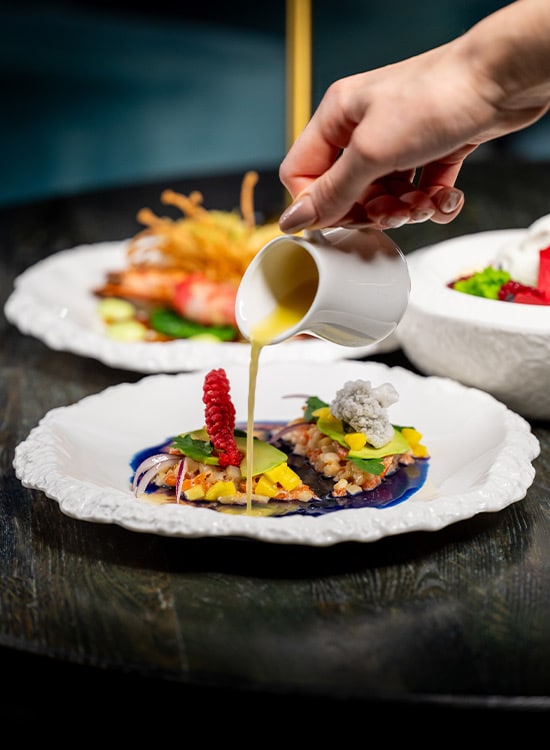 Plato de alta cocina con gambas mientras se vierte una salsa en un restaurante en Málaga