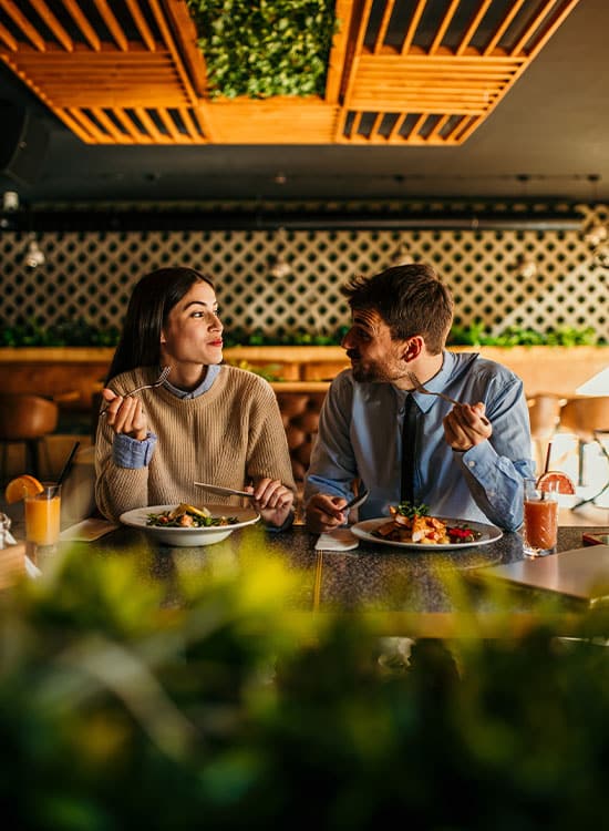 Pareja sonriente comiendo y conversando en la mesa de un restaurante en Málaga